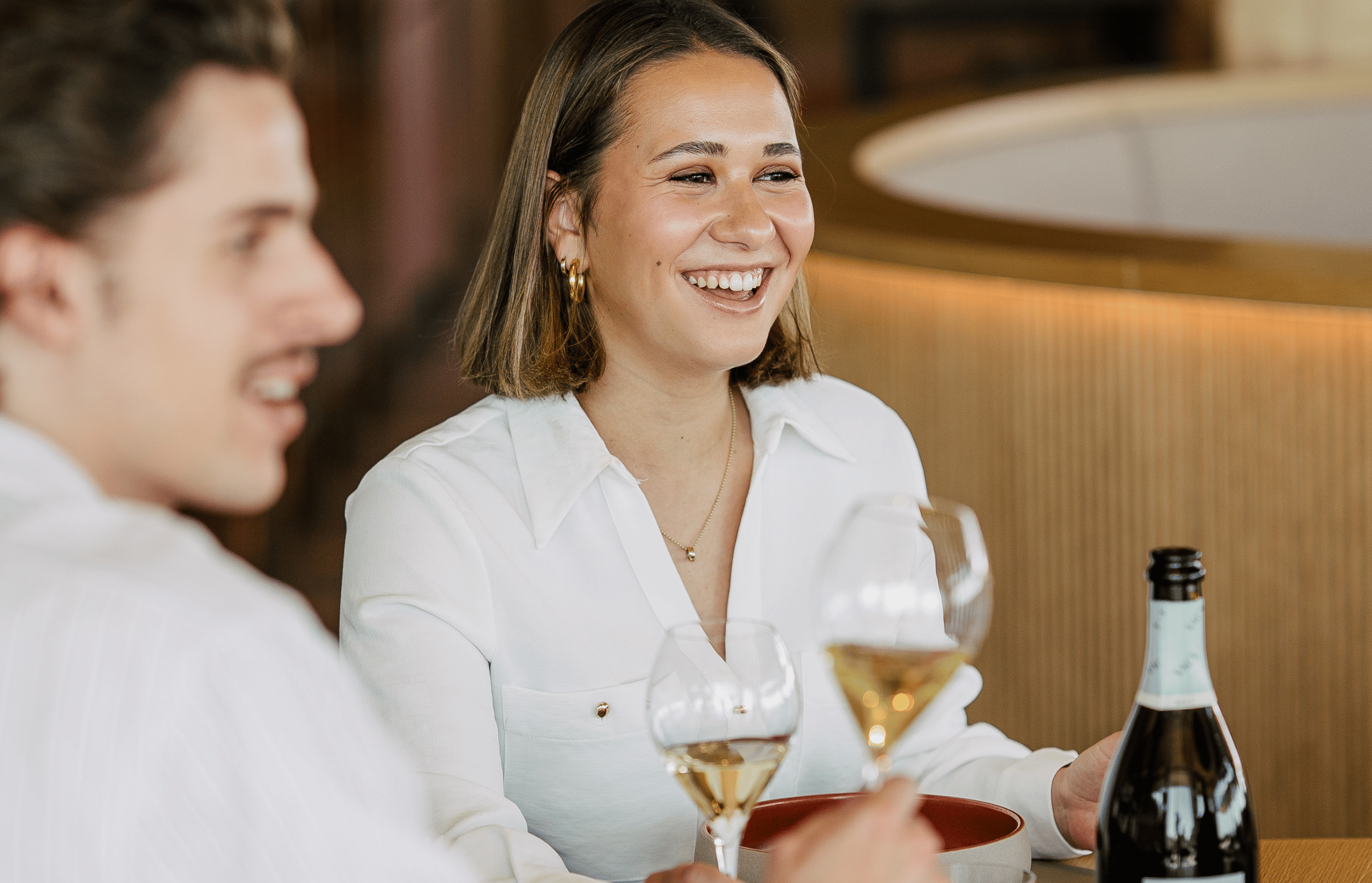 Ein mann und eine Frau die in die Ferne lächeln und ein Glas Sekt in der Hand halten